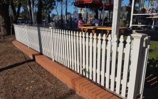 a white picket fence with a brick wall fencing supplier Sydney